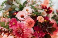 40 an extra bold wedding centerpiece of pink dahlias, orange dahlias, burgundy and purple blooms, dark foliage and greenery