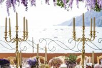 41 a luxurious wedding reception space with a lake view, a wisteria overhead installation, lilac, purple, blush blooms in pots and candelabras