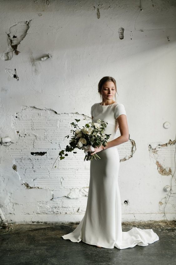 a timeless modern mermaid wedding dress of plain fabric, with a high neckline, short sleeves and a train is a lovely idea