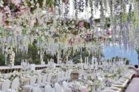 42 a luxurious wedding reception space with white furniture and pastel blooms on the tables and over the space, hanging down for creating a mood