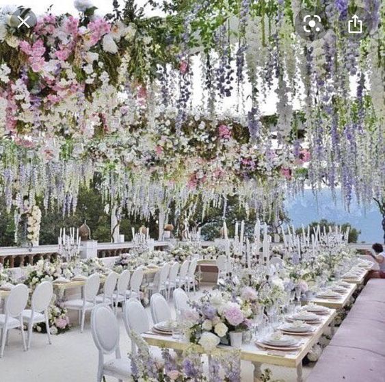 a luxurious wedding reception space with white furniture and pastel blooms on the tables and over the space, hanging down for creating a mood