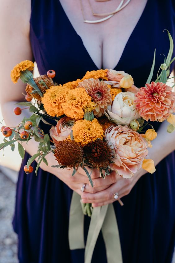 a bright fall wedding bouquet of roses, dahlias, mums and marigolds, berries and some greenery plus olive green ribbons
