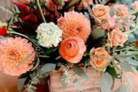 43 a bright fall wedding centerpiece of a wooden box with greenery, orange dahlias, ranunculus, greenery and some neutral blooms