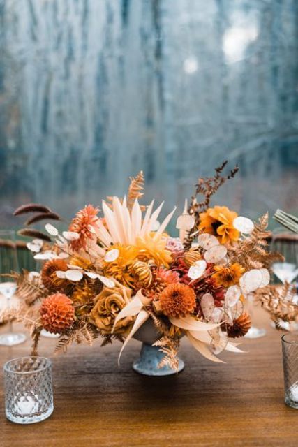 a beautiful fall wedding centerpiece of rust mums, yellow roses, fronds, lunaria and some dried leaves is amazing