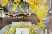 47 a wedding tablescape done in grey and yellow, with a mimosa wedding centerpiece and pampas grass, a woven placemat and yellow plates, yellow glasses