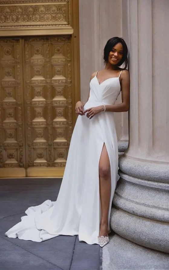 a fitting spaghetti strap wedding dress with a draped bodice, a pleated skirt with a slit and a train plus embellished shoes