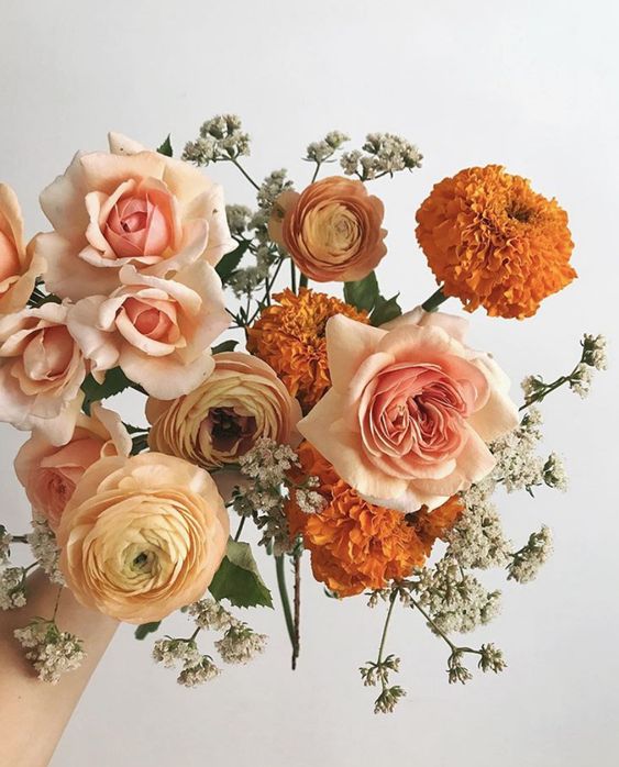 a chic wedding bouquet of marigolds, blush roses adn ranunculus plus some fillers is easy to make and cool