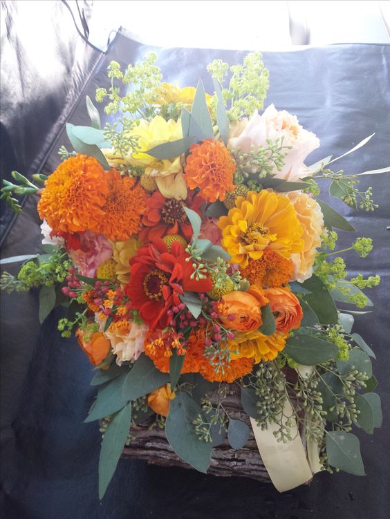 a colorful wedding bouquet of marigolds, dahlias and other blooms, greenery and leaves is a gorgeous idea for the fall