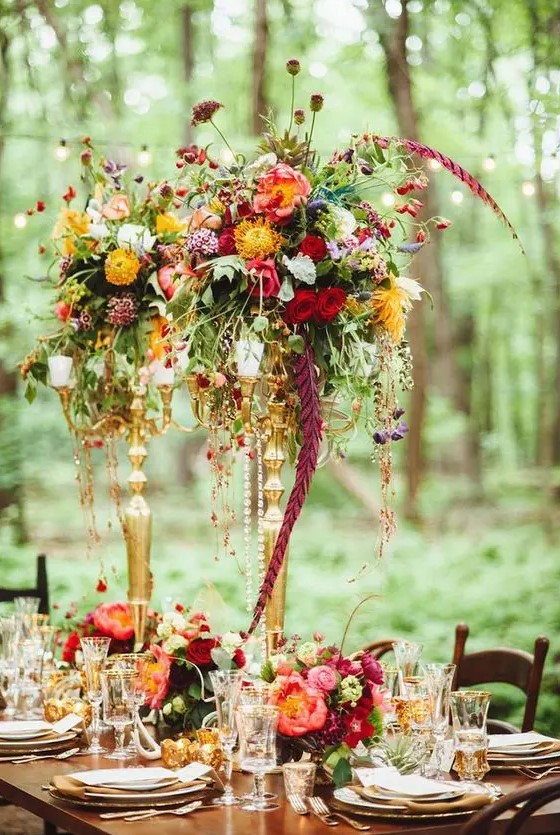 a colorful floral centerpiece of cascading blooms and greenery of various colors for a woodland wedding