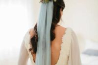 53 a lace sheath wedding dress with a cutout back and a floral headpiece with a powder blue veil to add a bit of color