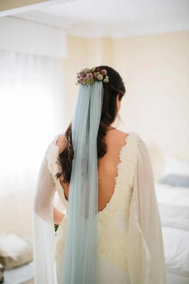 a lace sheath wedding dress with a cutout back and a floral headpiece with a powder blue veil to add a bit of color