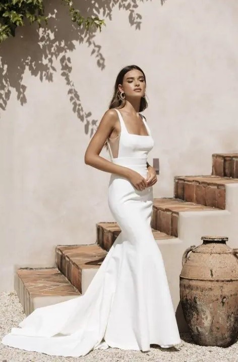 a minimalist plain mermaid wedding dress with a square neckline, sheer inserts on the sides, a train for an edgy bridal look