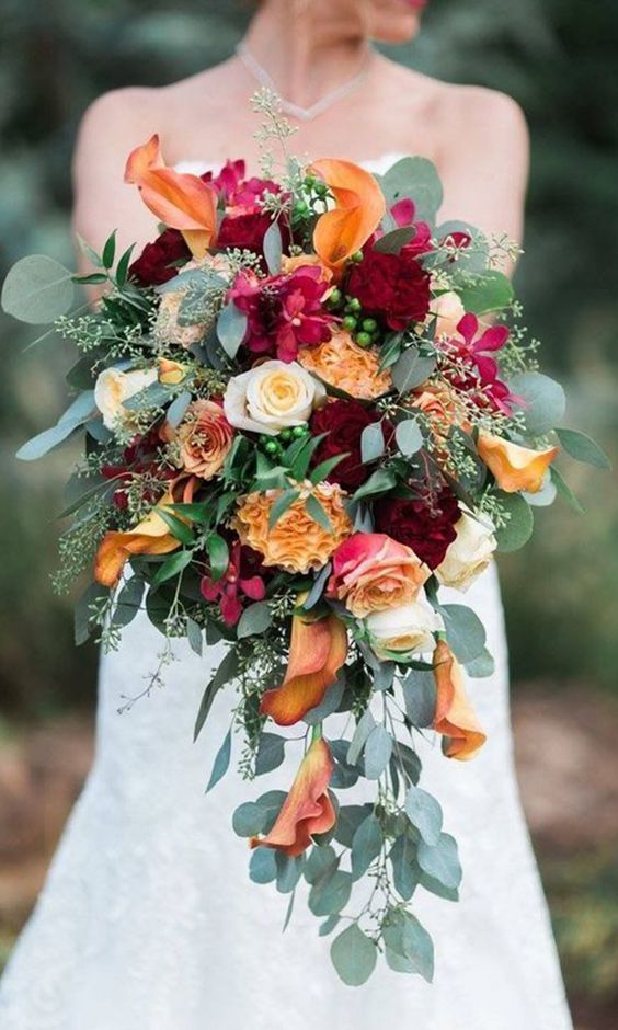 a contrasting wedding bouquet of pink and peachy roses, burgundy peonies, calla lilies, marigolds and greenery is amazing for the fall