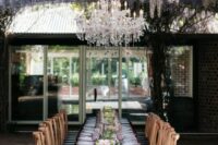 54 an outdoor wedding reception space with wisteria hanging over the table, a large crystal chandelier, a refined tablescape with a lilac tablecloth
