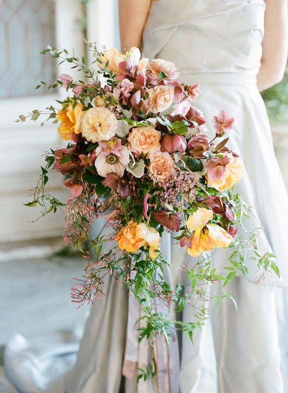 a dreamy cascading wedding bouquet of mauve and peachy blooms, marigolds, greenery and fillers for a fine art wedding