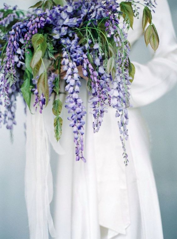 a lovely cascading wisteria wedding bouquet with greenery is a catchy idea for a spring wedding with a pastel color scheme