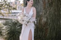 56 a modern glam bride wearing a plain A-line wedding dress with no sleeves, a deep neckline and a front slit, nude shoes and statement earrings