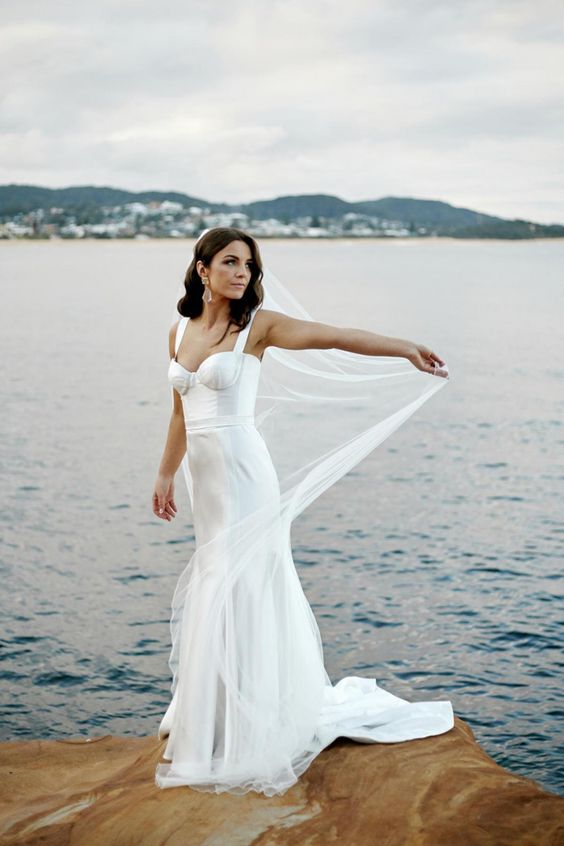 a modern glam mermaid wedding dress with a corset and a train plus a veil are a lovely combo for a modern glam bride