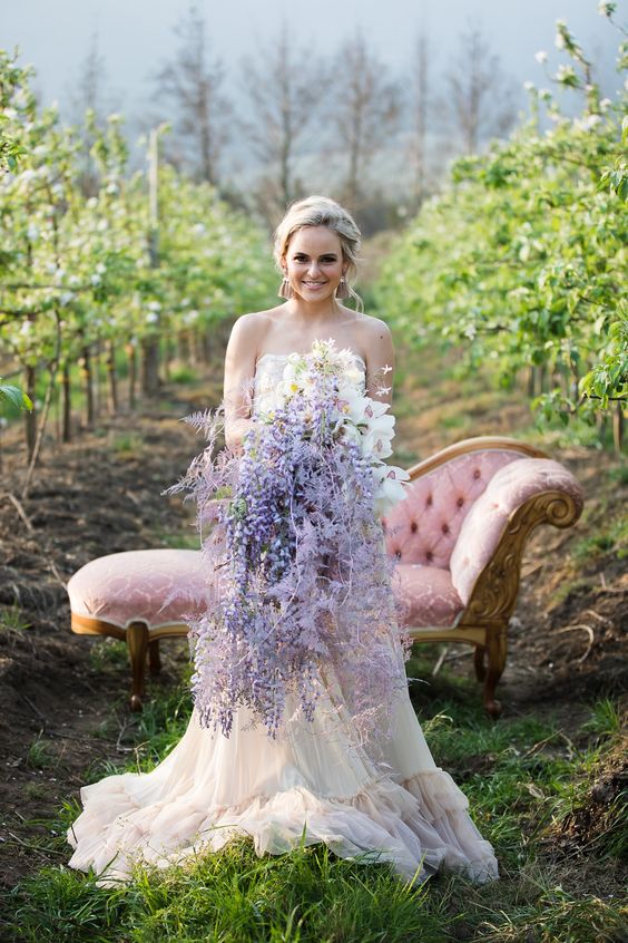 a unique cascading wedding bouquet of wisteria, white orchids and dried leaves spray painted lilac is wow