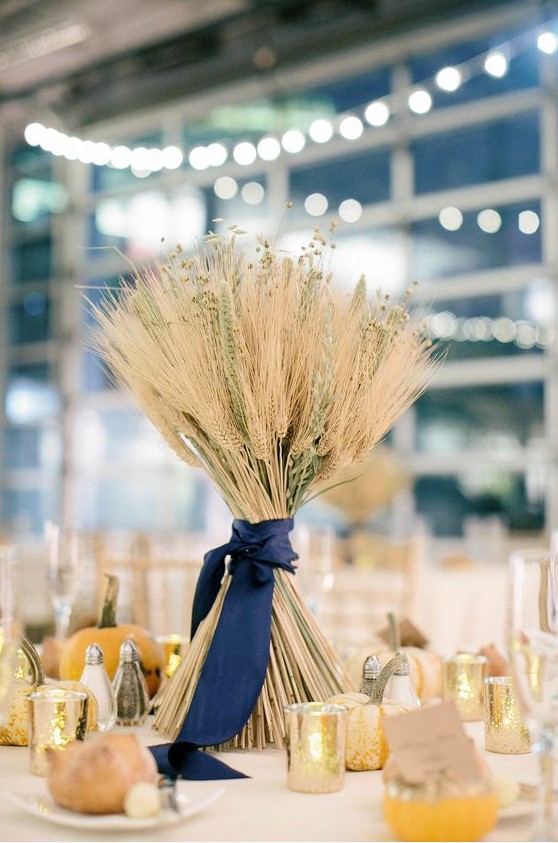 a cute wheat wedding centerpiece with dried blooms and pumpkins around is a cool idea for a rustic fall wedding