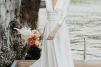 59 a modern plain A-line wedding dress with a deep neckline, a high waist and a pleated skirt with a train for a modern wedding