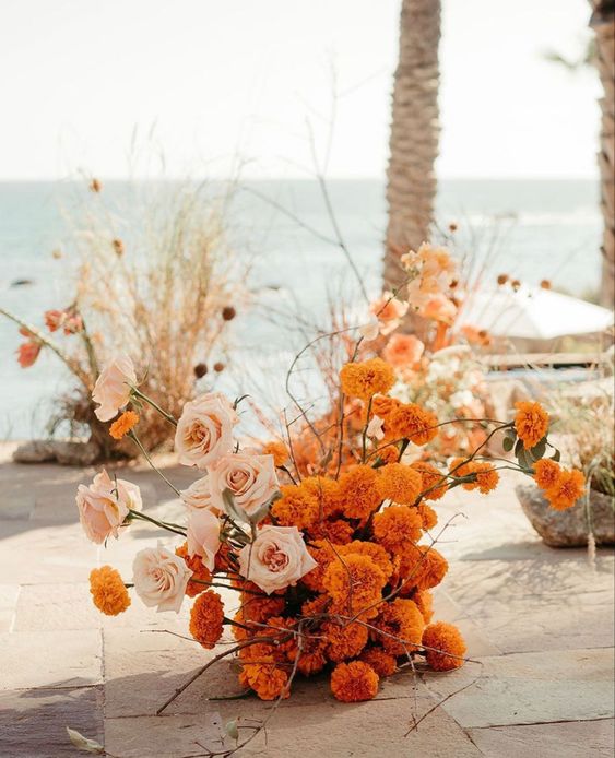 a bold floral wedding arrangement of marigolds and blush roses is a great idea of a centerpiece, wedding altar or just aisle arrangement