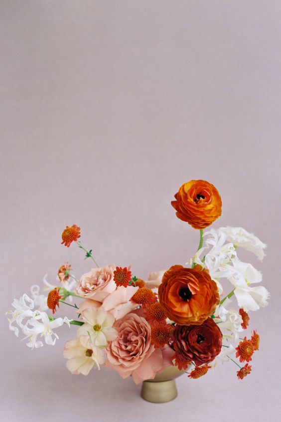 a gorgeous fine art wedding centerpiece of white, blush and orange blooms including mums and ranunculus is a refined wedding idea