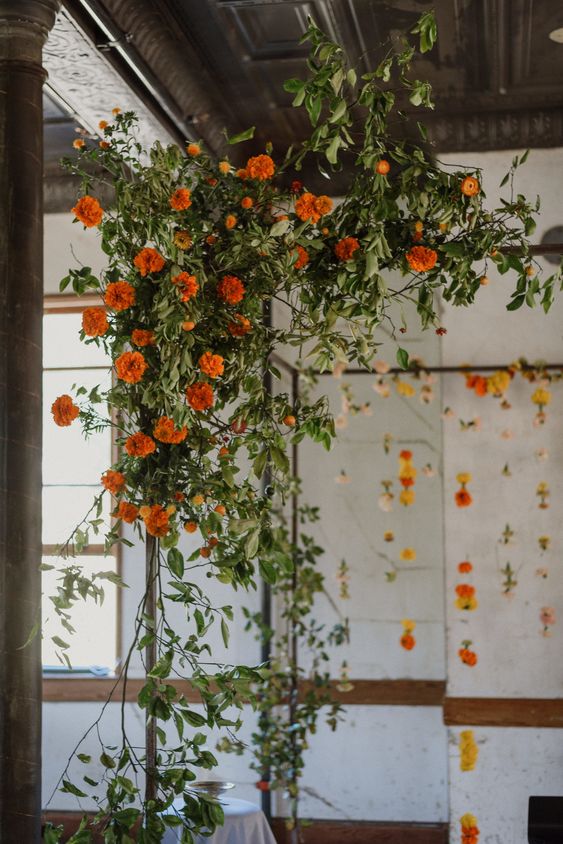 a bright wedding arch of greenery and marigolds is a cool idea for a summer wedding or a fall one