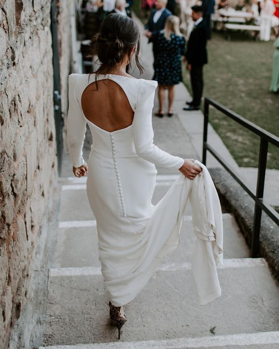 a modern plain wedding dress with accented shoulders, a cutout back and a row of buttons plus a train is a gorgeous and chic idea