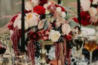 65 a lush moody wedding centerpiece of blush and red blooms, dark grapes and pomegranates plus black candles