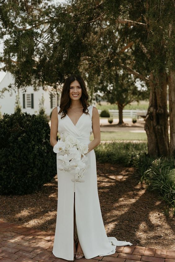 a modern wedding dress with thick straps, a V-neckline, a draped bodice, a front slit and a train is a lovely and elegant idea
