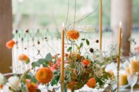 69 a pretty fall wedding centerpiece of white and orange blooms, greenery and orange candles is refined and chic