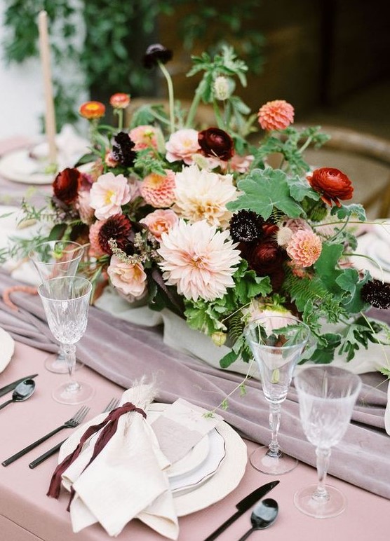 a refined autumn wedding centerpiece of leaves, blush, red and burgundy blooms is very elegant