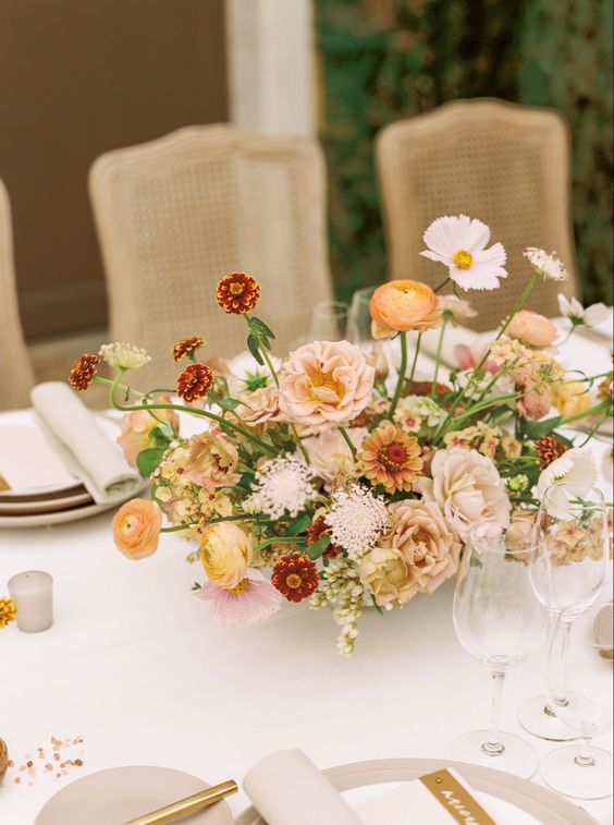 a refined muted color fall wedding centerpiece of white, blush, yellow and burgundy blooms and greenery is a lovely and delicate idea