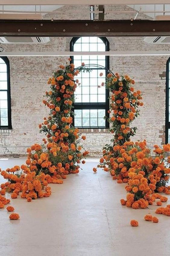 a super lush wedding arch covered with greenery and marigolds that are extended along it, too, is a fantastic idea for the fall