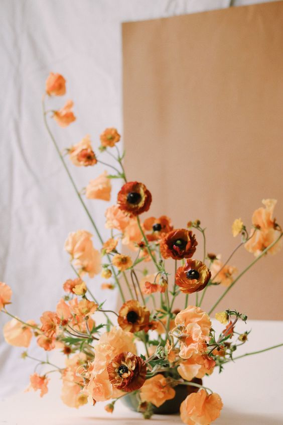 a sophisticated fall wedding centerpiece of orange poppies and some rust ranunculus is a beautiful fine art wedding idea