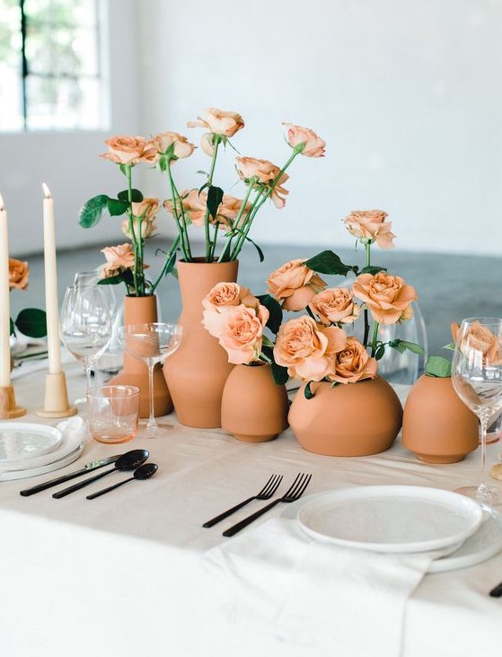a terracotta wedding centerpiece of a cluster of matching vases and roses of the same shade is very catchy