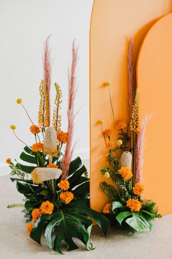 bold modern floral arrangements of fronds, marigolds, pink pampas grass and billy balls are fun for a modern wedding