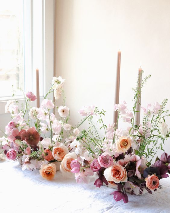 a beautiful and chic wedding centerpiece of blush sweet peas, pink and peachy peony roses, purple and pink tulips and greenery for spring