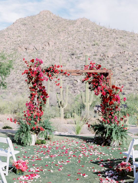 a beautiful and natural wedding arch covered with bougainvillea and roses plus ferns in pots at the base is a cool idea for a boho desert wedding