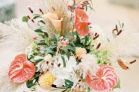 a beautiful and textural wedding centerpiece of white and yellow blooms, anthuriums, grasses, callas, berries and greenery