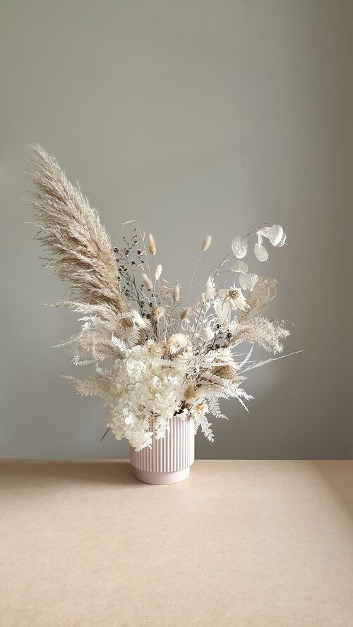 a beautiful modern wedding centerpiece of white hydrangeas, pampas grass, bunny tails, lunaria and various bleached leaves