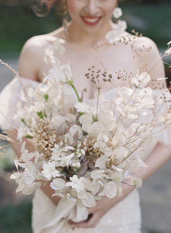 a beautiful white wedding bouquet of lunaria, some dried blooms and grasses is a dimensional solution for a spring or summer wedding