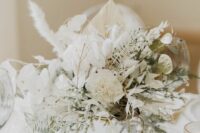 a beautiful white wedding centerpiece on a gold frame, with white carnations, orchids, lunaria, greenery and pampas grass is chic