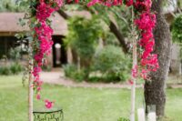 a birch wedding arbor covered with greenery and bougainvillea, with pillar candles on both sides is a lovely idea