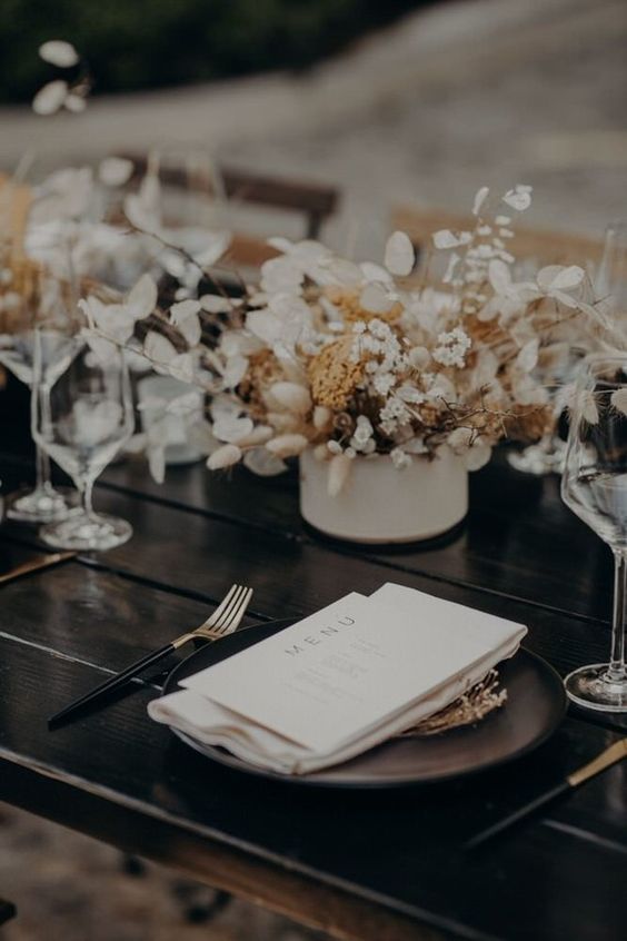 a black wedding tablescape with a white wedding centerpiece of lunaria, bunny tails, some fillers is a cool and contrasting solution