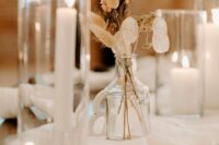 a boho wedding centerpiece of some blooms, lunaria, bunny tails plus candles around is a cool idea for a neutral boho wedding