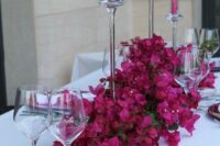 a bold and catchy wedding centerpiece of bougainvillea and matching candles is a stunning idea for a bright summer wedding