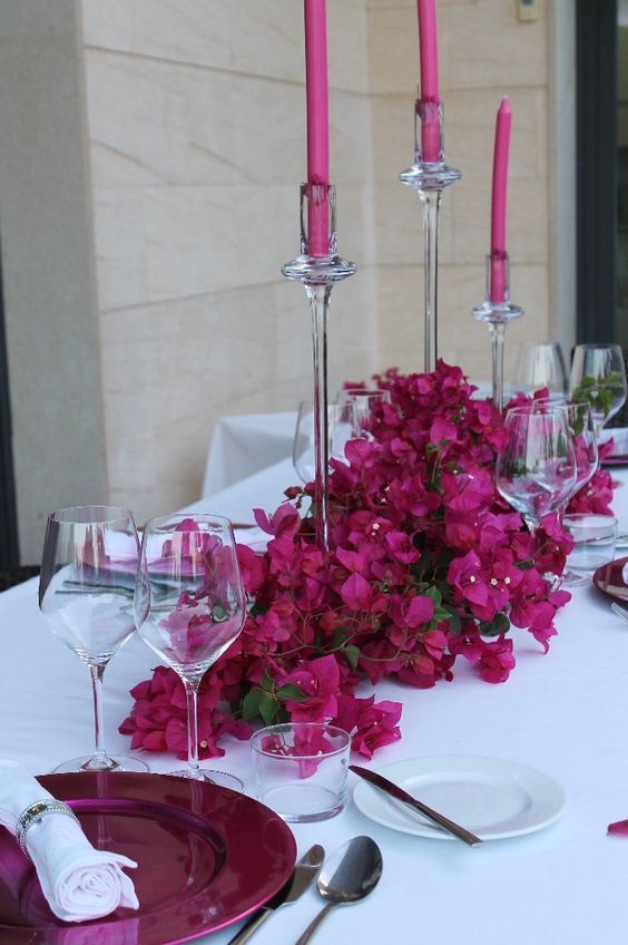 a bold and catchy wedding centerpiece of bougainvillea and matching candles is a stunning idea for a bright summer wedding