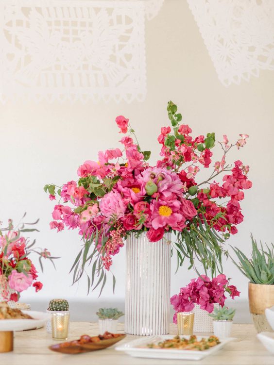a bold and lush wedding centerpiece of pink and coral peonies and bougainvillea plus cacti and agaves around is a stunning idea